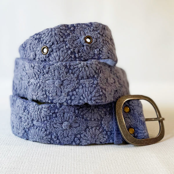 Photo of monochromatic hand-embroidered floral wool belt by Jenny Krauss, made in Peru with lead-free metal buckle. Versatile design with five sets of 2" spaced holes for hip or waist wear, featuring slight stretch for comfort.