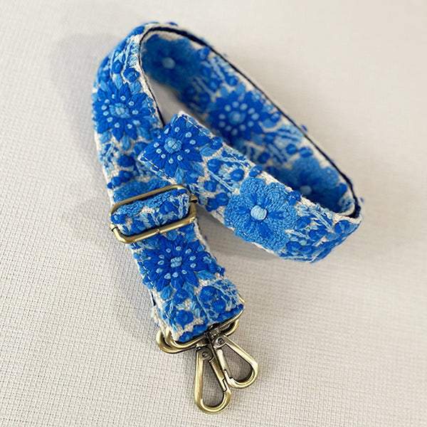 Photo of Jenny Krauss hand-embroidered wool strap from Peru. Multi-functional design serves as a bag or camera strap. Vibrant floral pattern, lead-free metal hardware, and adjustable length for versatile use. Elevate your style with this artisanal accessory.