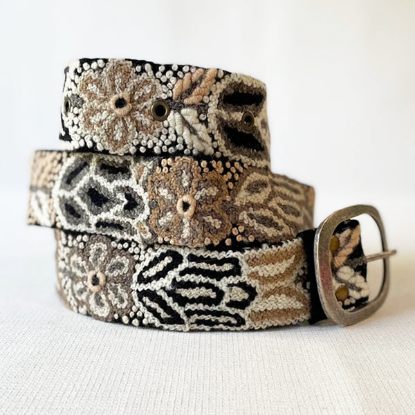 Photo of monochromatic hand-embroidered floral wool belt by Jenny Krauss, made in Peru with lead-free metal buckle. Versatile design with five sets of 2" spaced holes for hip or waist wear, featuring slight stretch for comfort.