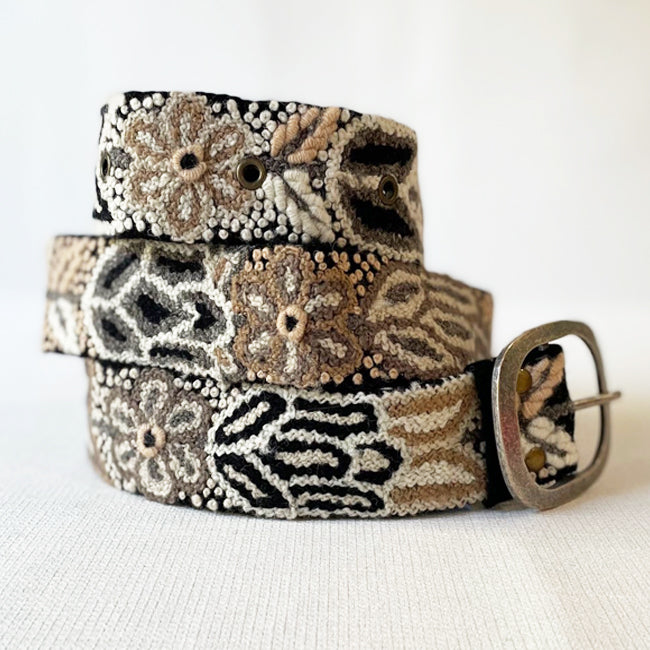 Photo of monochromatic hand-embroidered floral wool belt by Jenny Krauss, made in Peru with lead-free metal buckle. Versatile design with five sets of 2" spaced holes for hip or waist wear, featuring slight stretch for comfort.