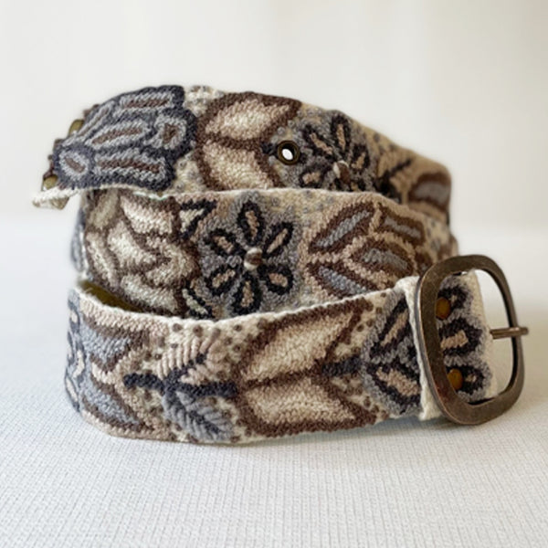 Photo of monochromatic hand-embroidered floral wool belt by Jenny Krauss, made in Peru with lead-free metal buckle. Versatile design with five sets of 2" spaced holes for hip or waist wear, featuring slight stretch for comfort.