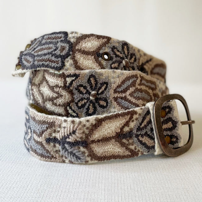 Photo of monochromatic hand-embroidered floral wool belt by Jenny Krauss, made in Peru with lead-free metal buckle. Versatile design with five sets of 2" spaced holes for hip or waist wear, featuring slight stretch for comfort.