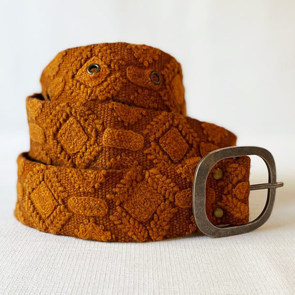Photo of monochromatic hand-embroidered floral wool belt by Jenny Krauss, made in Peru with lead-free metal buckle. Versatile design with five sets of 2" spaced holes for hip or waist wear, featuring slight stretch for comfort.