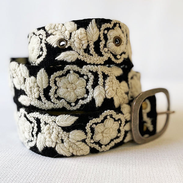 Photo of monochromatic hand-embroidered floral wool belt by Jenny Krauss, made in Peru with lead-free metal buckle. Versatile design with five sets of 2" spaced holes for hip or waist wear, featuring slight stretch for comfort.