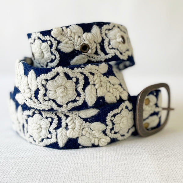 Photo of monochromatic hand-embroidered floral wool belt by Jenny Krauss, made in Peru with lead-free metal buckle. Versatile design with five sets of 2" spaced holes for hip or waist wear, featuring slight stretch for comfort.