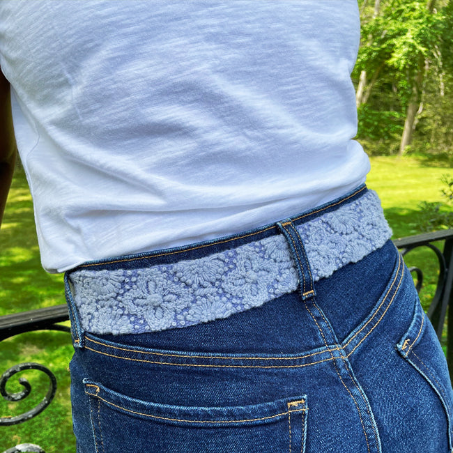 Photo of monochromatic hand-embroidered floral wool belt by Jenny Krauss, made in Peru with lead-free metal buckle. Versatile design with five sets of 2" spaced holes for hip or waist wear, featuring slight stretch for comfort.