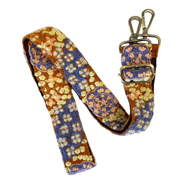 Photo of Jenny Krauss hand-embroidered wool bag strap from Peru. Multi-functional design serves as a camera or guitar strap. Vibrant floral pattern, lead-free metal hardware, and adjustable length for versatile use. Elevate your style with this artisanal accessory.