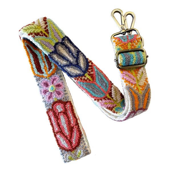 Photo of Jenny Krauss hand-embroidered wool bag strap from Peru. Multi-functional design serves as a camera or guitar strap. Vibrant floral pattern, lead-free metal hardware, and adjustable length for versatile use. Elevate your style with this artisanal accessory.