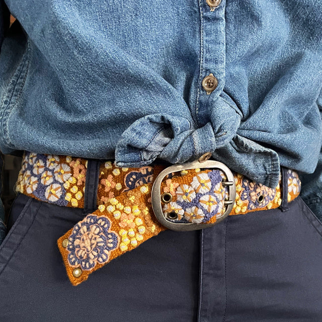 Photo of colorful hand-embroidered floral wool belt by Jenny Krauss, made in Peru with lead-free metal buckle. Versatile design with five sets of 2" spaced holes for hip or waist wear, featuring slight stretch for comfort.