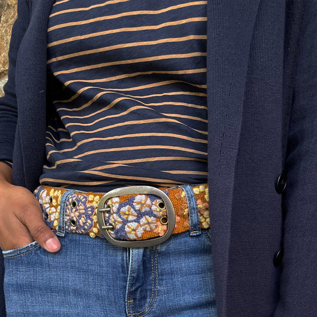Photo of colorful hand-embroidered floral wool belt by Jenny Krauss, made in Peru with lead-free metal buckle. Versatile design with five sets of 2" spaced holes for hip or waist wear, featuring slight stretch for comfort.
