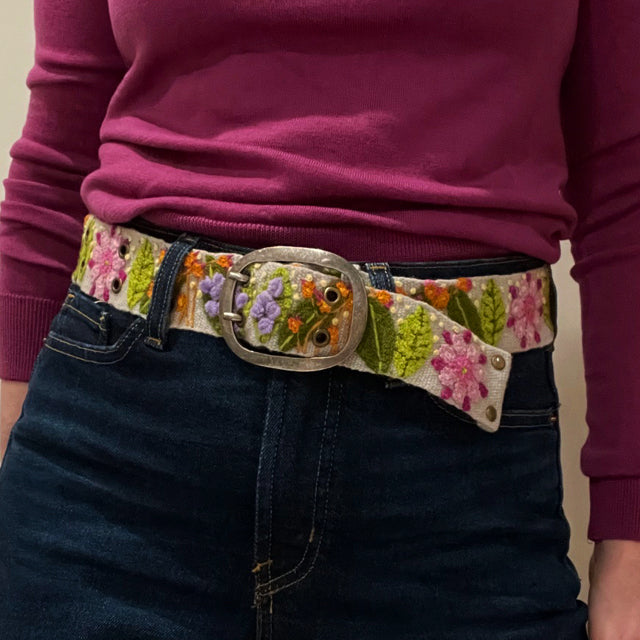 Photo of colorful hand-embroidered floral wool belt by Jenny Krauss, made in Peru with lead-free metal buckle. Versatile design with five sets of 2" spaced holes for hip or waist wear, featuring slight stretch for comfort.