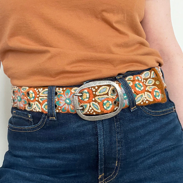 Photo of colorful hand-embroidered floral wool belt by Jenny Krauss, made in Peru with lead-free metal buckle. Versatile design with five sets of 2" spaced holes for hip or waist wear, featuring slight stretch for comfort.