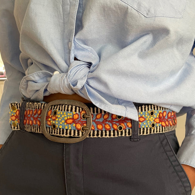 Photo of colorful hand-embroidered floral wool belt by Jenny Krauss, made in Peru with lead-free metal buckle. Versatile design with five sets of 2" spaced holes for hip or waist wear, featuring slight stretch for comfort.