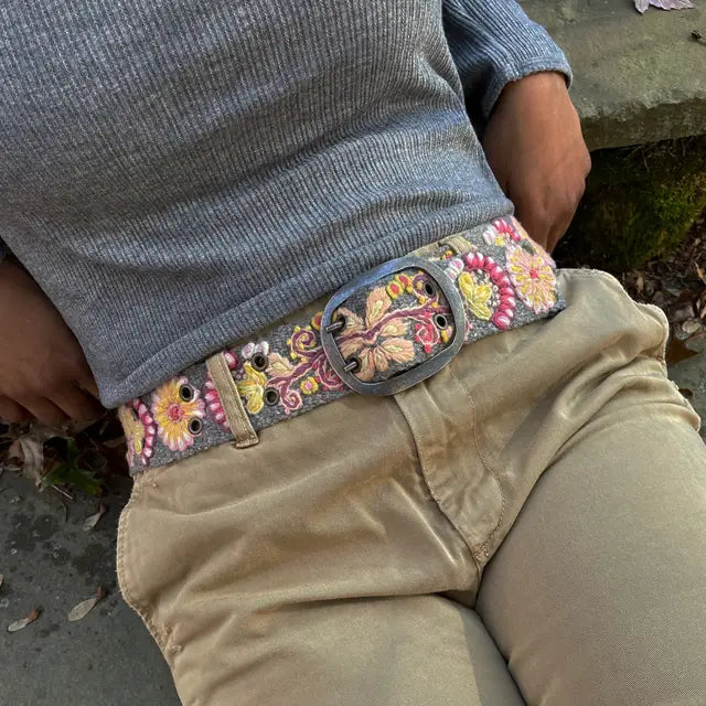 Photo of colorful hand-embroidered floral wool belt by Jenny Krauss, made in Peru with lead-free metal buckle. Versatile design with five sets of 2" spaced holes for hip or waist wear, featuring slight stretch for comfort.