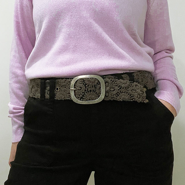 Photo of monochromatic hand-embroidered floral wool belt by Jenny Krauss, made in Peru with lead-free metal buckle. Versatile design with five sets of 2" spaced holes for hip or waist wear, featuring slight stretch for comfort.