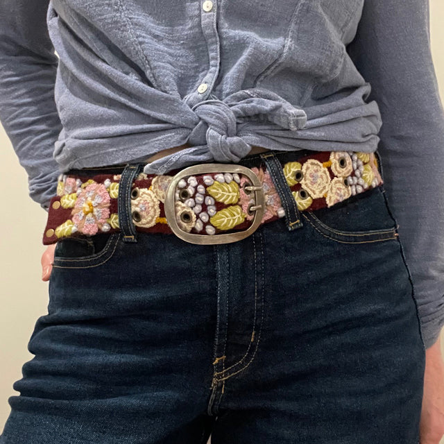 Photo of colorful hand-embroidered floral wool belt by Jenny Krauss, made in Peru with lead-free metal buckle. Versatile design with five sets of 2" spaced holes for hip or waist wear, featuring slight stretch for comfort.