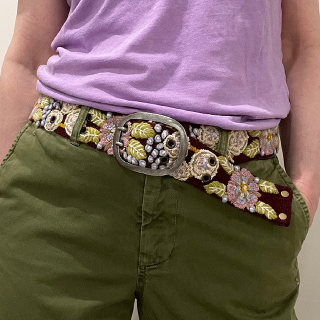 Photo of colorful hand-embroidered floral wool belt by Jenny Krauss, made in Peru with lead-free metal buckle. Versatile design with five sets of 2" spaced holes for hip or waist wear, featuring slight stretch for comfort.