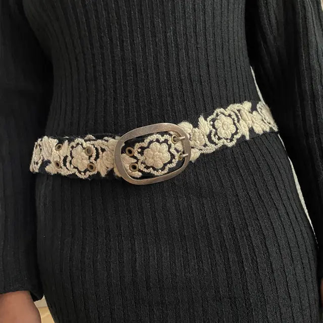 Photo of monochromatic hand-embroidered floral wool belt by Jenny Krauss, made in Peru with lead-free metal buckle. Versatile design with five sets of 2" spaced holes for hip or waist wear, featuring slight stretch for comfort.