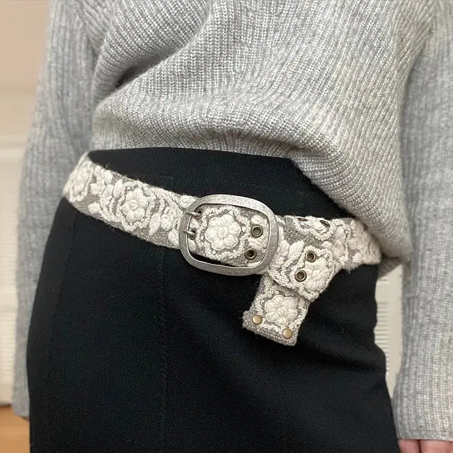 Photo of monochromatic hand-embroidered floral wool belt by Jenny Krauss, made in Peru with lead-free metal buckle. Versatile design with five sets of 2" spaced holes for hip or waist wear, featuring slight stretch for comfort.
