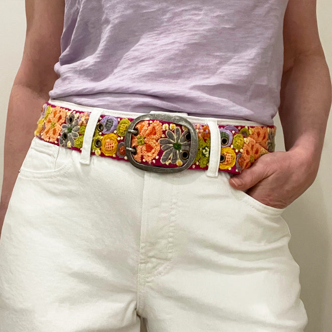 Photo of colorful hand-embroidered floral wool belt by Jenny Krauss, made in Peru with lead-free metal buckle. Versatile design with five sets of 2" spaced holes for hip or waist wear, featuring slight stretch for comfort.