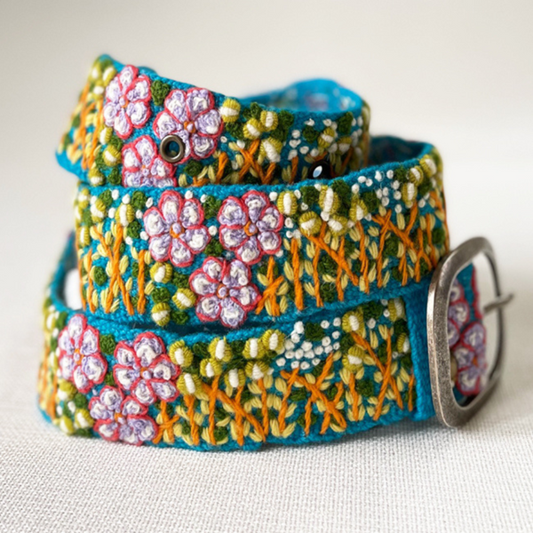 Photo of colorful hand-embroidered floral wool belt by Jenny Krauss, made in Peru with lead-free metal buckle. Versatile design with five sets of 2" spaced holes for hip or waist wear, featuring slight stretch for comfort.