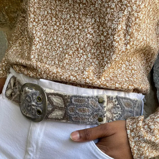 Photo of monochromatic hand-embroidered floral wool belt by Jenny Krauss, made in Peru with lead-free metal buckle. Versatile design with five sets of 2" spaced holes for hip or waist wear, featuring slight stretch for comfort.
