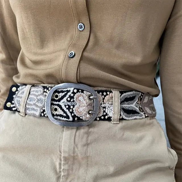 Photo of monochromatic hand-embroidered floral wool belt by Jenny Krauss, made in Peru with lead-free metal buckle. Versatile design with five sets of 2" spaced holes for hip or waist wear, featuring slight stretch for comfort.