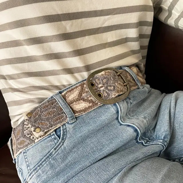 Photo of monochromatic hand-embroidered floral wool belt by Jenny Krauss, made in Peru with lead-free metal buckle. Versatile design with five sets of 2" spaced holes for hip or waist wear, featuring slight stretch for comfort.