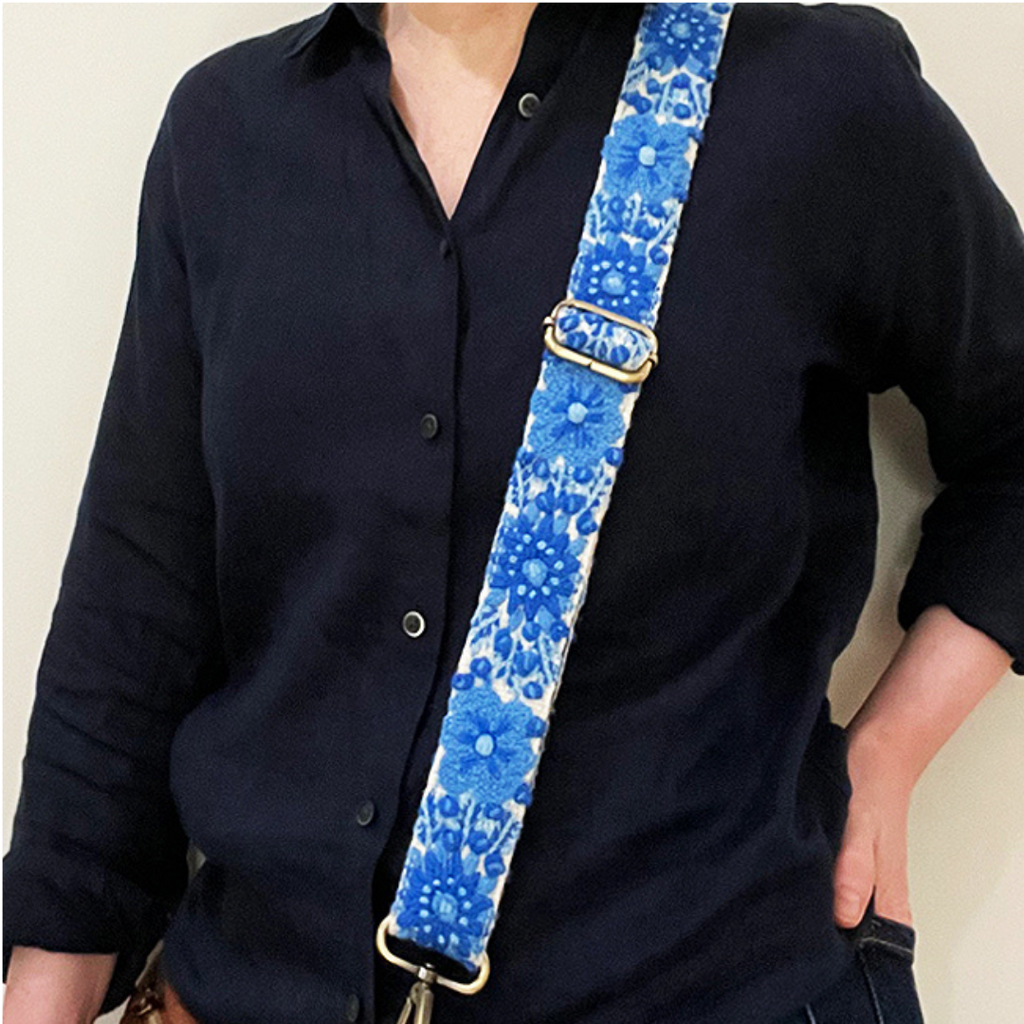 Photo of Jenny Krauss hand-embroidered wool strap from Peru. Multi-functional design serves as a bag or camera strap. Vibrant floral pattern, lead-free metal hardware, and adjustable length for versatile use. Elevate your style with this artisanal accessory.