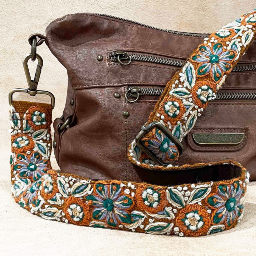 Photo of Jenny Krauss hand-embroidered wool strap from Peru. Multi-functional design serves as a bag or camera strap. Vibrant floral pattern, lead-free metal hardware, and adjustable length for versatile use. Elevate your style with this artisanal accessory.