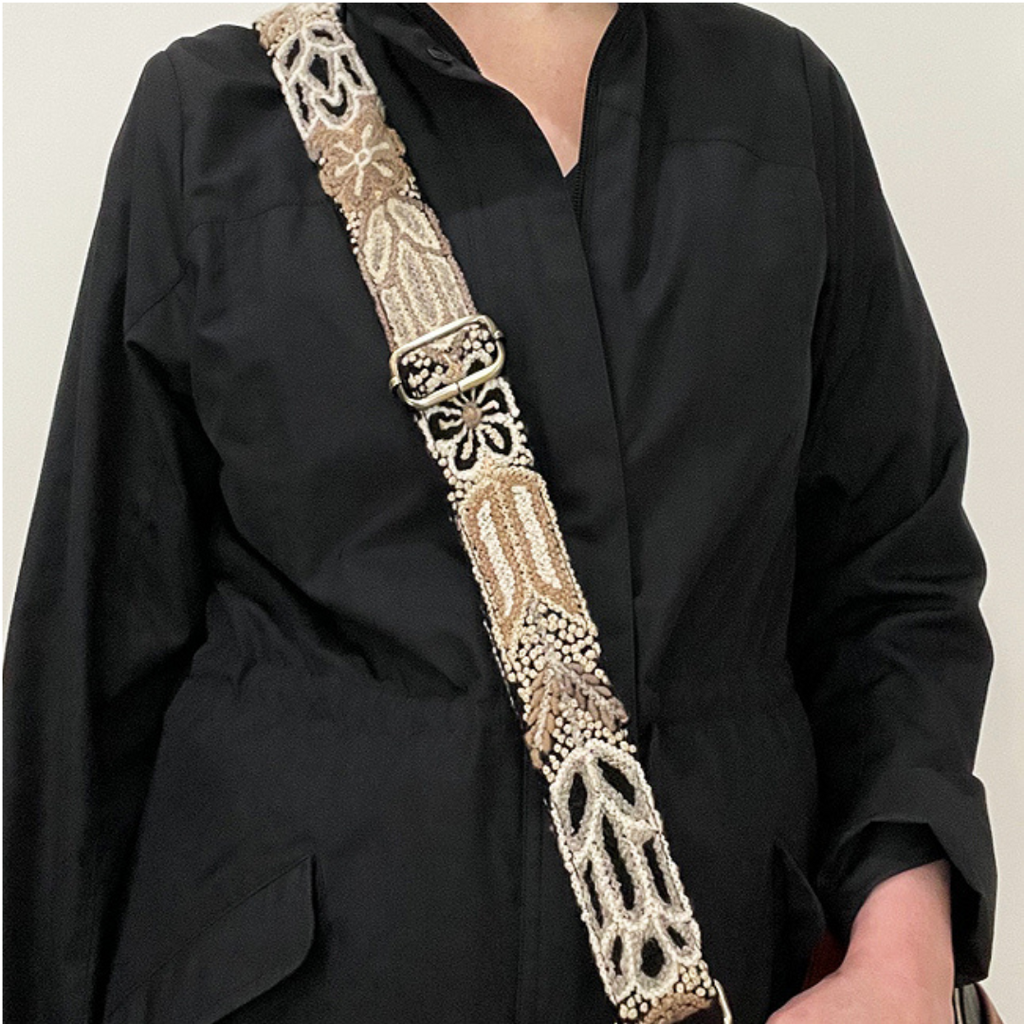 Photo of Jenny Krauss hand-embroidered wool strap from Peru. Multi-functional design serves as a camera or bag strap. Monochromatic floral pattern, lead-free metal hardware, and adjustable length for versatile use. Elevate your style with this artisanal accessory.