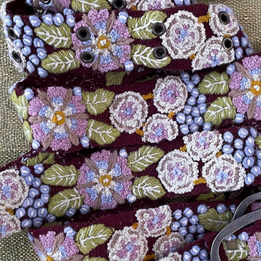 Photo of colorful hand-embroidered floral wool belt by Jenny Krauss, made in Peru with lead-free metal buckle. Versatile design with five sets of 2" spaced holes for hip or waist wear, featuring slight stretch for comfort.