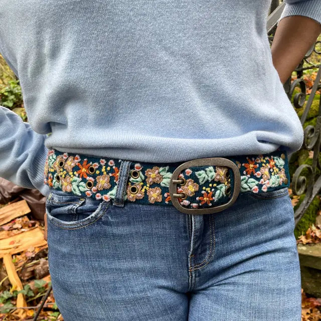Photo of colorful hand-embroidered floral wool belt by Jenny Krauss, made in Peru with lead-free metal buckle. Versatile design with five sets of 2" spaced holes for hip or waist wear, featuring slight stretch for comfort.
