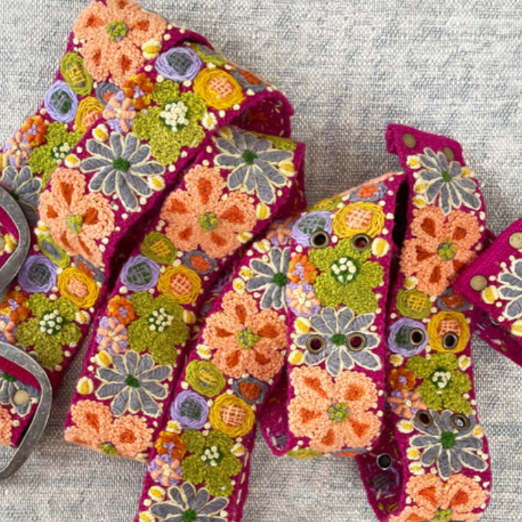 Photo of colorful hand-embroidered floral wool belt by Jenny Krauss, made in Peru with lead-free metal buckle. Versatile design with five sets of 2" spaced holes for hip or waist wear, featuring slight stretch for comfort.