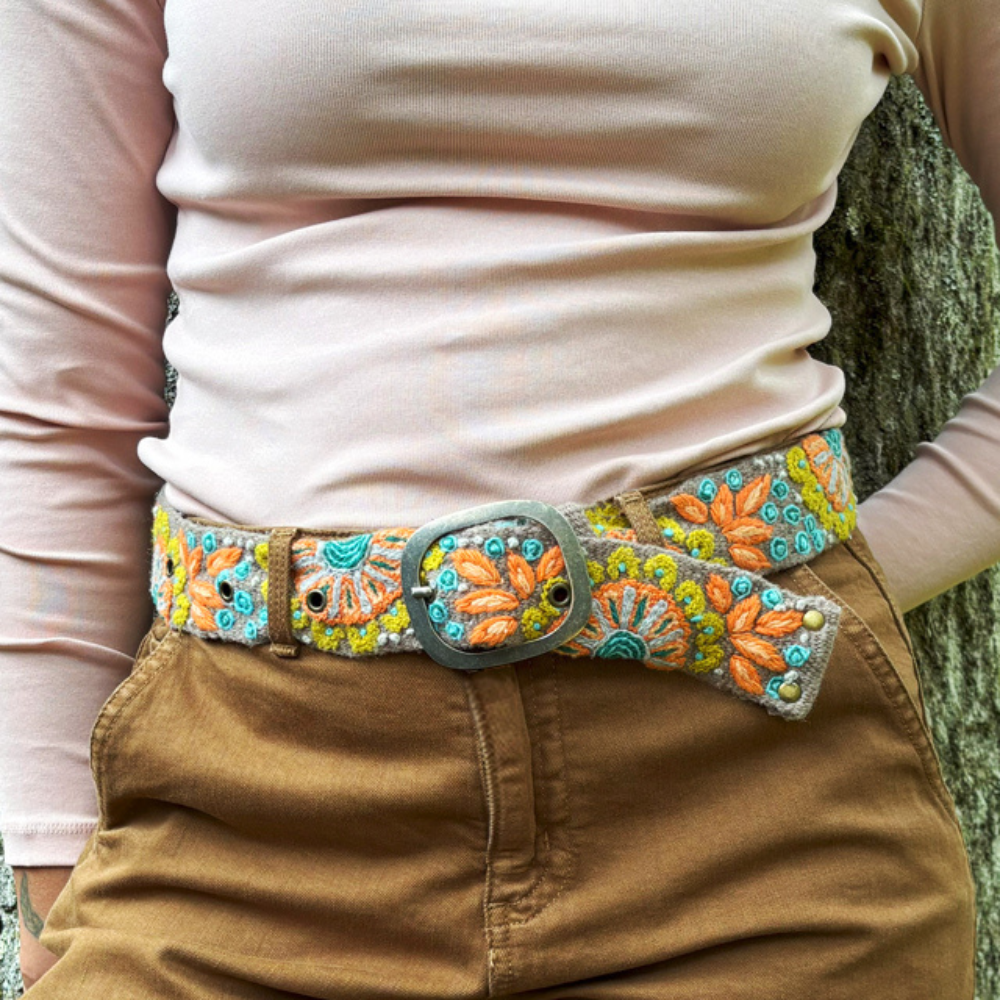 Photo of colorful hand-embroidered floral wool belt by Jenny Krauss, made in Peru with lead-free metal buckle. Versatile design with five sets of 2" spaced holes for hip or waist wear, featuring slight stretch for comfort.