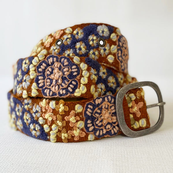 Photo of colorful hand-embroidered floral wool belt by Jenny Krauss, made in Peru with lead-free metal buckle. Versatile design with five sets of 2" spaced holes for hip or waist wear, featuring slight stretch for comfort.