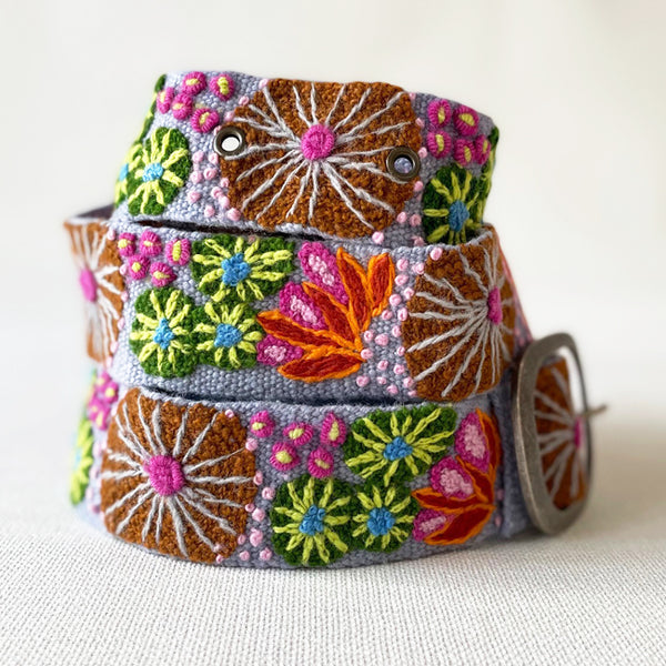 Photo of colorful hand-embroidered floral wool belt by Jenny Krauss, made in Peru with lead-free metal buckle. Versatile design with five sets of 2" spaced holes for hip or waist wear, featuring slight stretch for comfort.