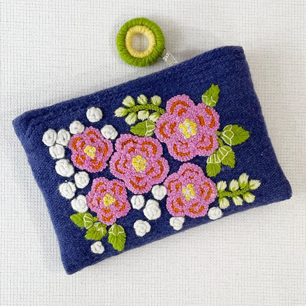 Photo of Jenny Krauss embroidered wool pouch, multi-functional travel accessory. Handcrafted with 100% wool, cotton lining, and sturdy metal zipper. Versatile for use as a wallet, clutch, or keepsake bag. Measures 5.5" L x 8" W. Designed in the U.S.A. and handmade in Peru by skilled artisans.
