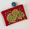 Photo of Jenny Krauss embroidered wool pouch, multi-functional travel accessory. Handcrafted with 100% wool, cotton lining, and sturdy metal zipper. Versatile for use as a wallet, clutch, or keepsake bag. Measures 5.5" L x 8" W. Designed in the U.S.A. and handmade in Peru by skilled artisans.