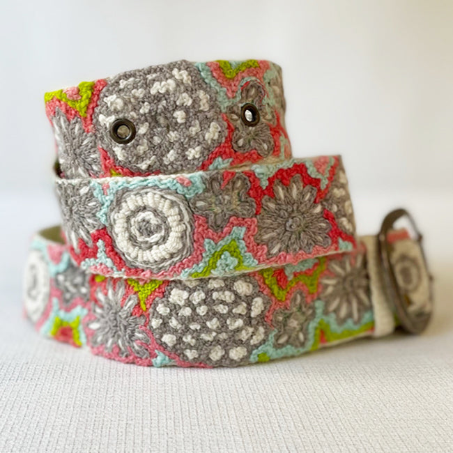 Photo of colorful hand-embroidered floral wool belt by Jenny Krauss, made in Peru with lead-free metal buckle. Versatile design with five sets of 2" spaced holes for hip or waist wear, featuring slight stretch for comfort.