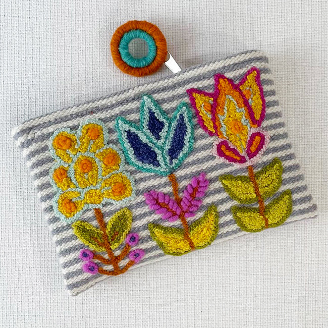 Photo of Jenny Krauss embroidered wool pouch, multi-functional travel accessory. Handcrafted with 100% wool, cotton lining, and sturdy metal zipper. Versatile for use as a wallet, clutch, or keepsake bag. Measures 5.5" L x 8" W. Designed in the U.S.A. and handmade in Peru by skilled artisans.