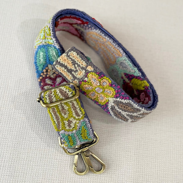 Photo of Jenny Krauss hand-embroidered wool bag strap from Peru. Multi-functional design serves as a camera or guitar strap. Vibrant floral pattern, lead-free metal hardware, and adjustable length for versatile use. Elevate your style with this artisanal accessory.