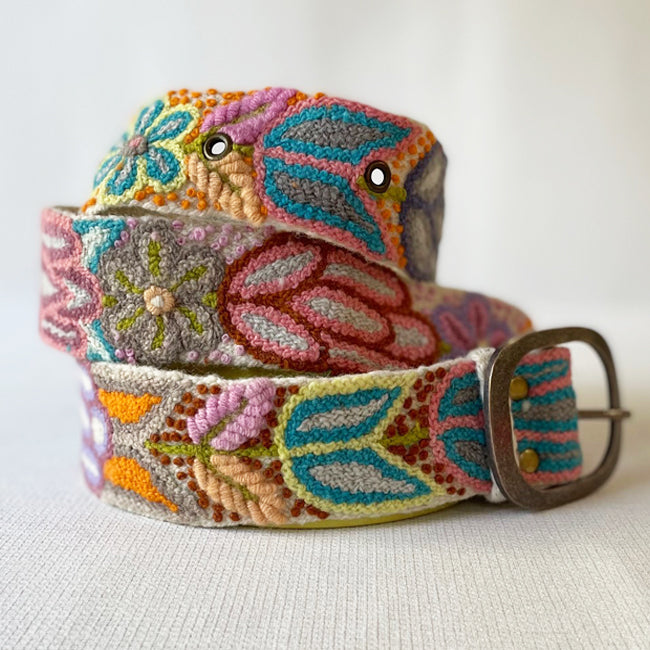 Photo of colorful hand-embroidered floral wool belt by Jenny Krauss, made in Peru with lead-free metal buckle. Versatile design with five sets of 2" spaced holes for hip or waist wear, featuring slight stretch for comfort.