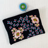 Photo of Jenny Krauss embroidered wool pouch, multi-functional travel accessory. Handcrafted with 100% wool, cotton lining, and sturdy metal zipper. Versatile for use as a wallet, clutch, or keepsake bag. Measures 5.5" L x 8" W. Designed in the U.S.A. and handmade in Peru by skilled artisans.