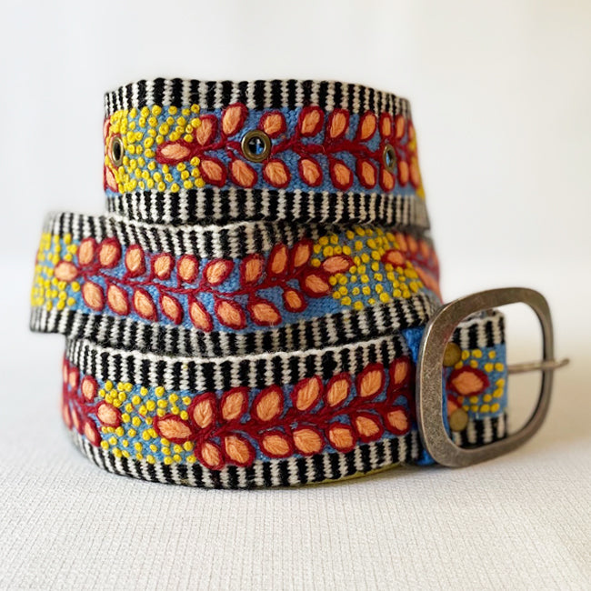 Photo of colorful hand-embroidered floral wool belt by Jenny Krauss, made in Peru with lead-free metal buckle. Versatile design with five sets of 2" spaced holes for hip or waist wear, featuring slight stretch for comfort.