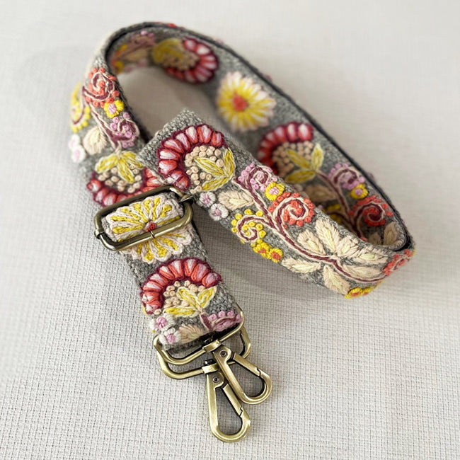 Photo of Jenny Krauss hand-embroidered wool strap from Peru. Multi-functional design serves as a bag or camera strap. Vibrant floral pattern, lead-free metal hardware, and adjustable length for versatile use. Elevate your style with this artisanal accessory.