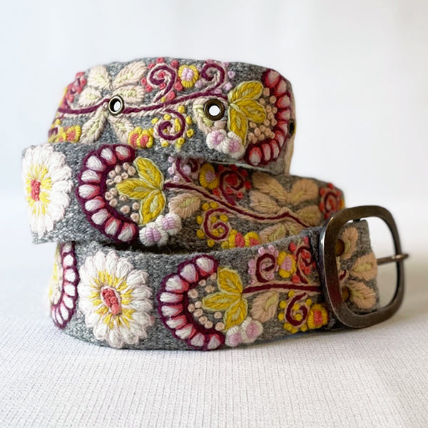 Photo of colorful hand-embroidered floral wool belt by Jenny Krauss, made in Peru with lead-free metal buckle. Versatile design with five sets of 2" spaced holes for hip or waist wear, featuring slight stretch for comfort.