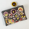 Photo of Jenny Krauss embroidered wool pouch, multi-functional travel accessory. Handcrafted with 100% wool, cotton lining, and sturdy metal zipper. Versatile for use as a wallet, clutch, or keepsake bag. Measures 5.5" L x 8" W. Designed in the U.S.A. and handmade in Peru by skilled artisans.