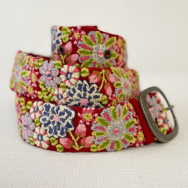 Photo of colorful hand-embroidered floral wool belt by Jenny Krauss, made in Peru with lead-free metal buckle. Versatile design with five sets of 2" spaced holes for hip or waist wear, featuring slight stretch for comfort.