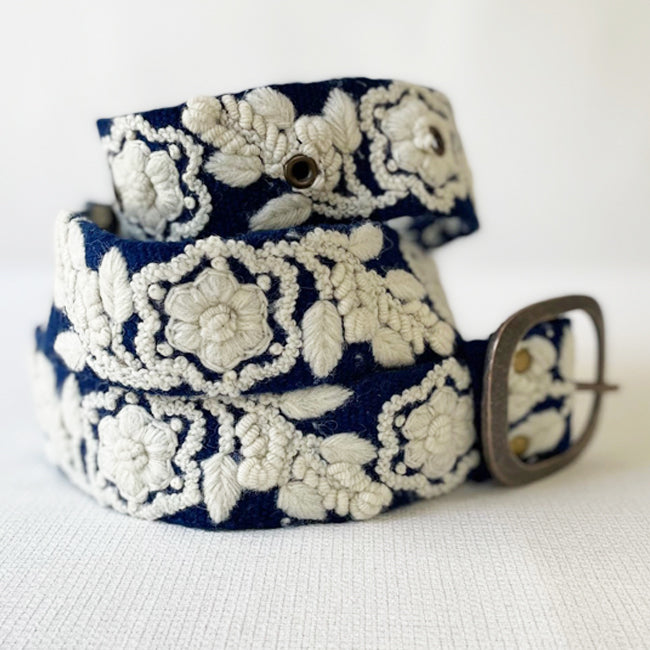 Photo of monochromatic  hand-embroidered floral wool belt by Jenny Krauss, made in Peru with lead-free metal buckle. Versatile design with five sets of 2" spaced holes for hip or waist wear, featuring slight stretch for comfort.